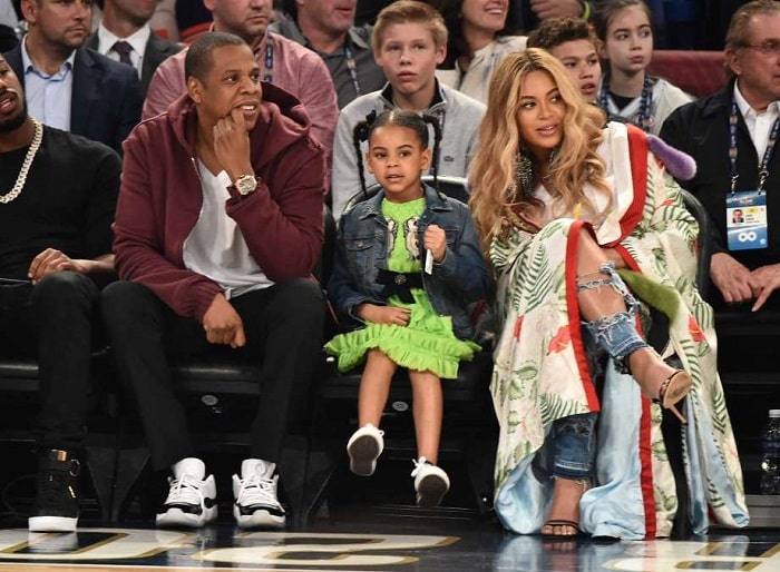 Blue Ivy Carter sitting with her parents Jay Z and Beyonce .