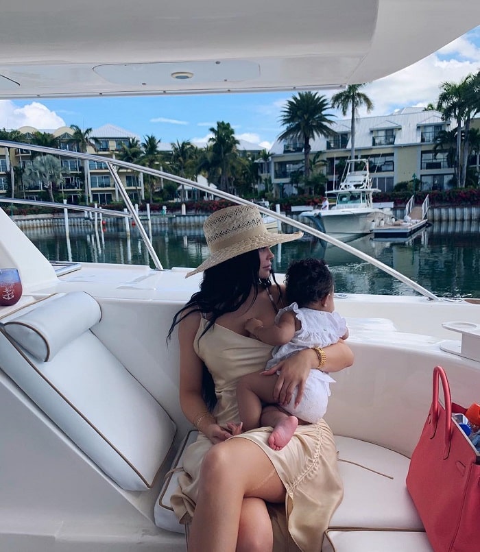 Kylie with her baby wearing a tan colored dress.
