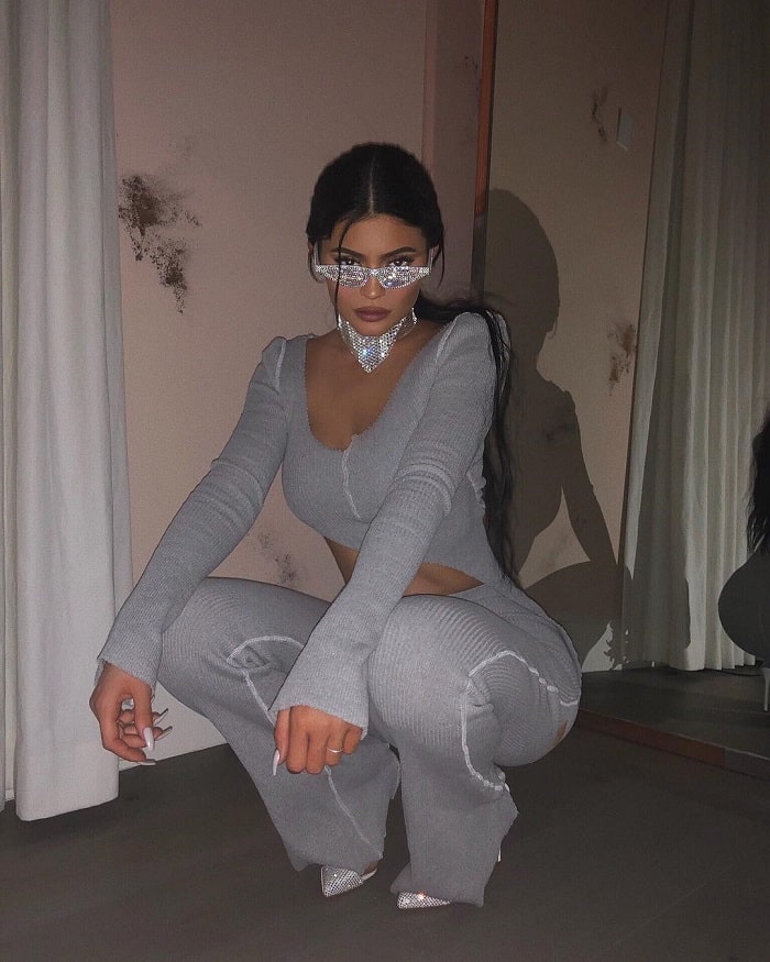 Kylie Jenner in crystal adorned shades and grey outfit.