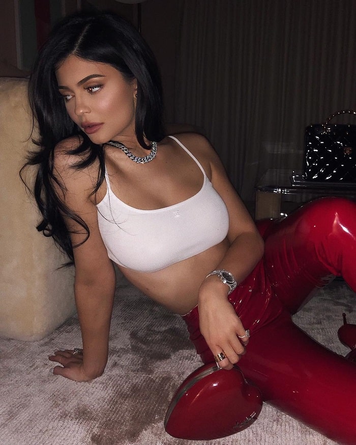 Kylie dressed in red leather pants and a white bra.