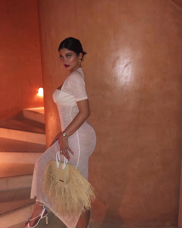 Kylie in a long white dress with red lips.