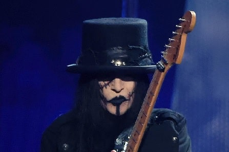 A picture of Mick Mars holding his guitar.