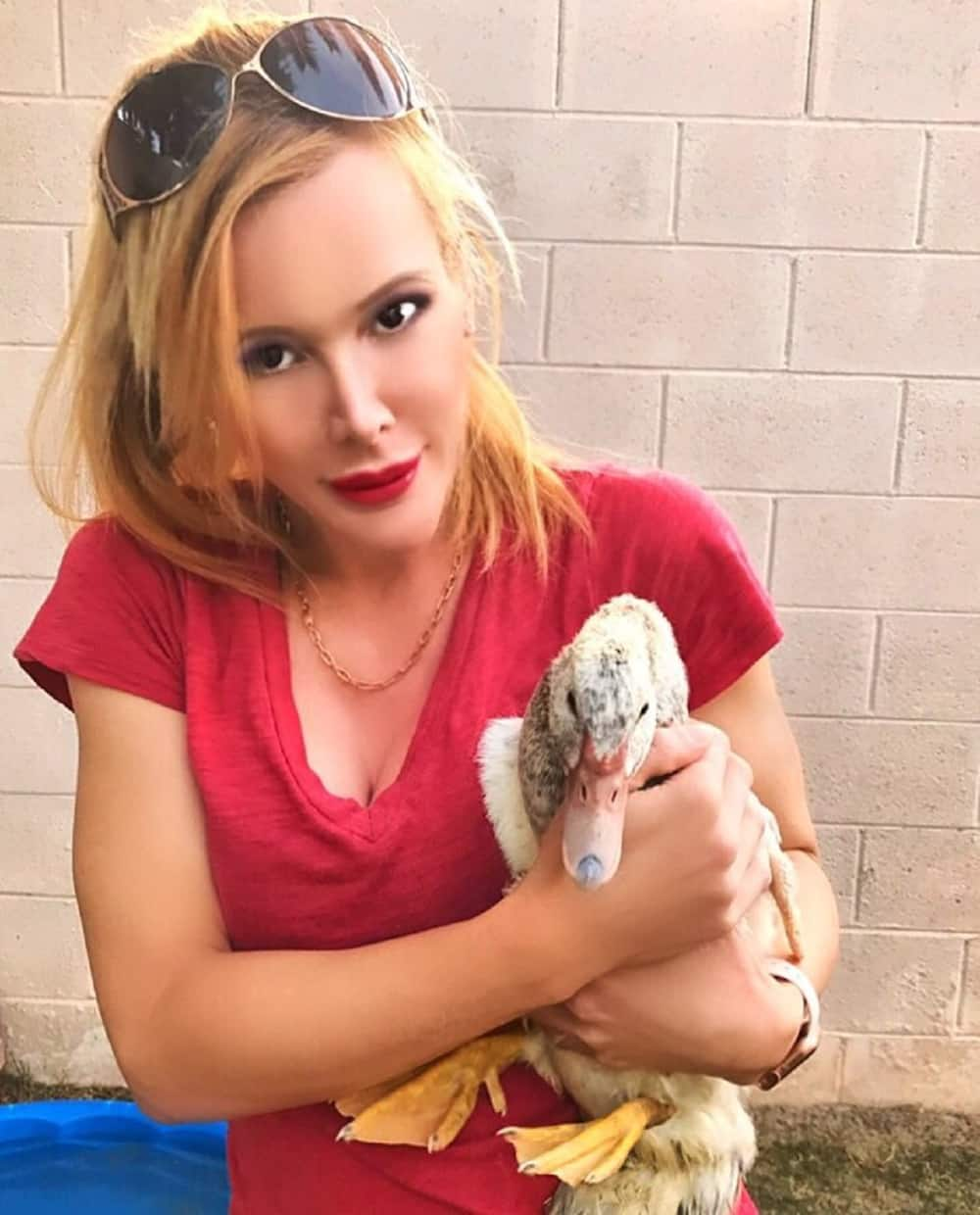 Genevieve Gallen holding her pet duck wearing a sunglasses and a red t-shirt