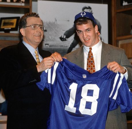 Peyton Manning holding his 18 number jersey. 